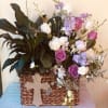 Basket arrangement of purple and white flowers with a cross decoration