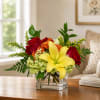Bouquet of red roses and a yellow lily in a clear square vase