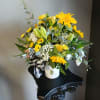 Yellow mixed bouquet in a white vase with a black-and-white ribbon