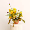 Mixed yellow and blue flowers in a small terracotta vase