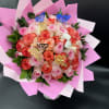 Round bouquet of pink and coral roses with butterfly accents wrapped in pink paper