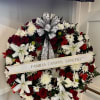 Standing round wreath of red roses, white lilies, and white mums with script ribbon on an easel