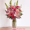 Tall pink arrangement with lilies, roses, and carnations in a clear rectangular glass vase
