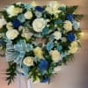 Heart-shaped wreath of white roses and blue carnations with a light blue ribbon bow
