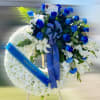 Standing white sympathy wreath with blue roses and ribbon on an easel