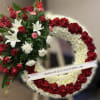 Standing wreath of red roses and white flowers with a side spray on a white ribbon banner.