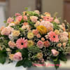 Low casket-style spray of pink and peach roses, gerberas, carnations, and mums with white filler flowers