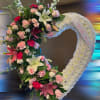 Open heart wreath of white flowers with pink roses, lilies, and carnations and a ‘With Love’ ribbon