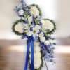 Standing cross of white mums with white lilies and roses, blue delphinium, and blue ribbon