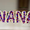 Funeral tribute letters spelling NANA in white flowers with purple and blue accents.
