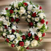 Circular wreath with white lilies, red roses, white mums, and red carnations
