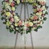 Large floral wreath of white mums and pink roses on a wooden easel with ivory ribbon.