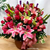 Large arrangement of pink lilies and mixed pink and red roses in a brown bowl vase