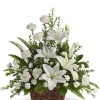 White lilies and carnations arranged in a wicker basket with abundant foliage