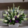 Tall basket arrangement of white roses and snapdragons with purple accents