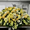 Large yellow and white casket spray with lilies, roses, daisies, and mums on a low rectangular base