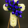 Standing white chrysanthemum cross with cluster of vivid blue roses on a wooden easel