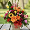 Colorful mixed flower arrangement in a woven basket with a red ribbon