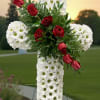 White floral cross with red roses on an outdoor stand