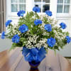 Blue carnations and white baby's breath in a glass vase with a blue ribbon