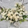 White rose and orchid arrangement in a striped container