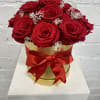 Red roses in a gold box with a red ribbon