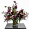Tall burgundy and purple floral arrangement in a clear glass vase