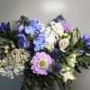 Bouquet of blue, white, and lavender flowers with dark greenery