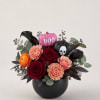 Halloween bouquet with roses, carnations, and pumpkins in a black vase