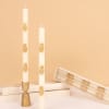 White taper candles with gold pineapple decorations in boxes