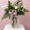 White calla lilies in a glass vase with a pink polka-dot bow