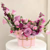 Pink and purple mixed flower arrangement in a pink handbag-style box