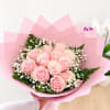 Handheld bouquet of pink roses wrapped in pink paper
