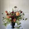 Mixed bouquet of peach and burgundy flowers in a black vase