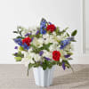 Patriotic-style arrangement of red roses, white lilies and mums, and blue flowers in a white vase