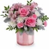 Pink roses and mixed blooms arranged in a pink glass vase
