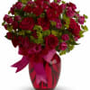 Bouquet of red and pink roses in a red glass vase with a ribbon