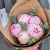 Bouquet of pale pink peonies wrapped in brown paper