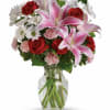 Bouquet of pink lilies, red roses, white daisies, and carnations in a glass vase