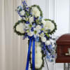 White and blue funeral spray with lilies and roses on a stand