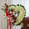 Heart-shaped floral wreath with red roses and white blooms on an easel