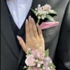 Pink rose boutonniere and wrist corsage on a black suit