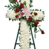 White floral cross with red roses and pink lilies on an easel