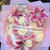 Heart-shaped bouquet of pink and cream roses with lilies and a Valentine ribbon