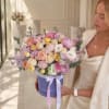 Woman holding a pastel mixed flower bouquet in a lavender hat box