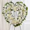 White floral heart wreath on a black stand with a ribbon bow