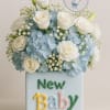 Blue and white floral arrangement in a baby-themed box with a welcome sign