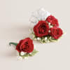 This elegant corsage and boutonniere set, featuring vibrant red blooms, is thoughtfully