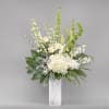 White floral arrangement in a tall marble vase with green accents