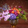 Colorful mixed bouquet in a round glass vase with orchids and hydrangeas